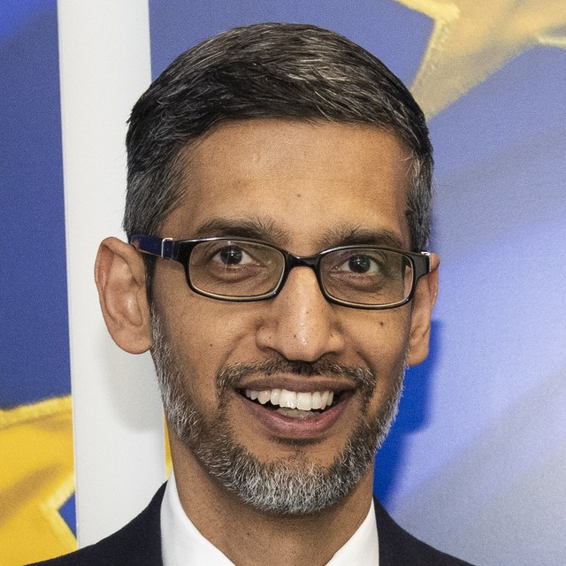 Google 執行長皮查伊穿深色西裝與藍色領帶、戴黑框眼鏡微笑看向鏡頭